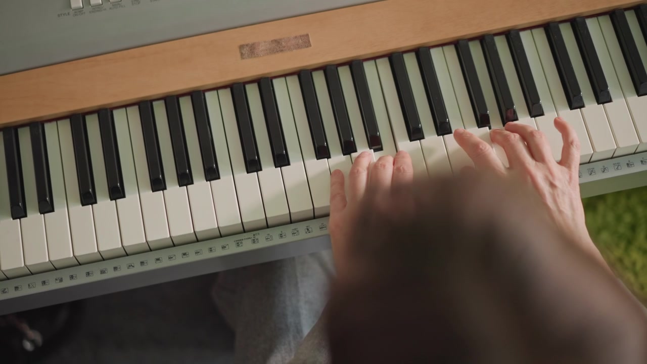 Overhead piano keys hands practicing scales student focused on technique, closeup of digital keyboard with wooden trim, fingers moving through scales and arpeggios, wrist alignment and posture