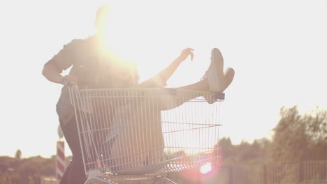 side view of a young man and woman having fun outdoors on shopping trolleys. multiethnic young people racing on shopping carts. on the parking zone with their