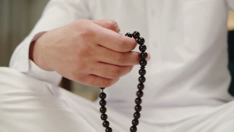 close-up of a muslim man's hand holding and counting prayer beads