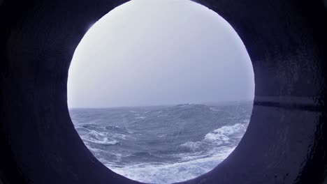 porthole view of big waves snow and high winds on the drakes passage heading south the antarctic