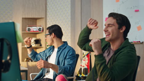 hombres alegres llamando por video en el lugar de trabajo moderno. compañeros de trabajo sonrientes dando cinco