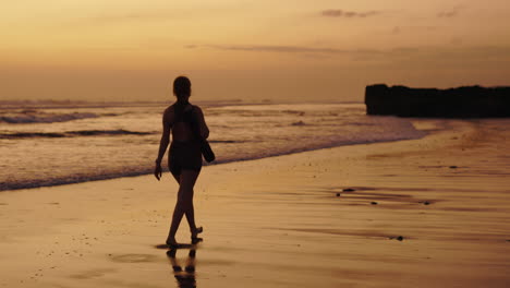 mujer caminando por la playa al atardecer