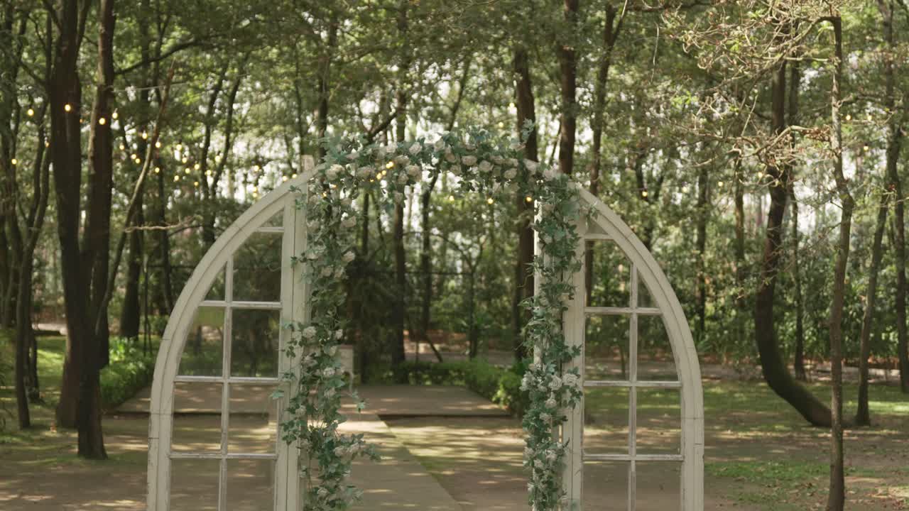 나무와 자연광으로 둘러싸인 로맨틱한 플로럴 웨딩 아치