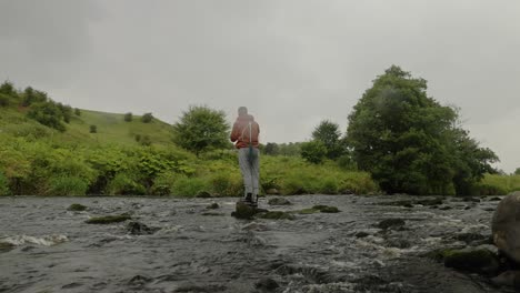 Static-shot-of-a-fly-fisherman-standing-on-a-rock-casting-into-a-creek