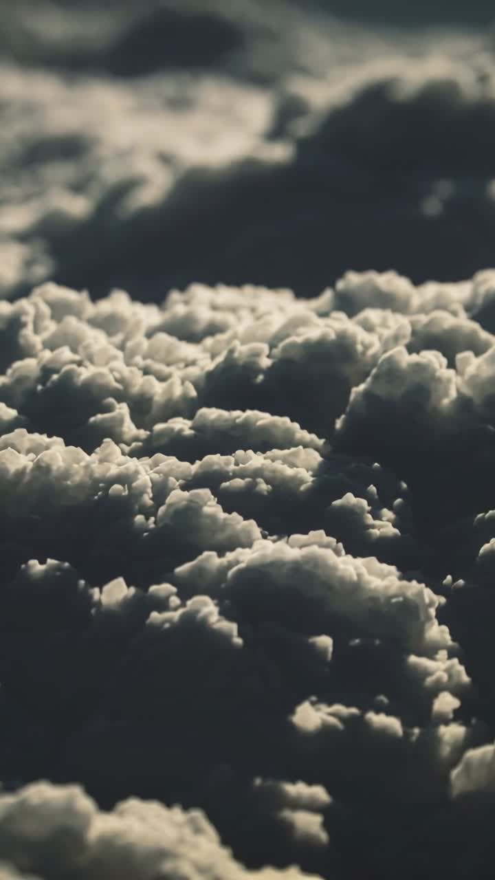 Telecamera che avanza sopra le nuvole, rivelando cime di cumuli illuminate dal sole e ombre profonde, per il design tecnologico.