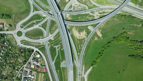 an aerial drone footage captures intricate highway junction with cars navigating complex roundabouts and intersecting roads