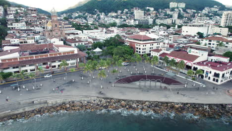 the-boardwalk-of-Puerto-Vallarta,-with-the-city,-church,-mountains,-and-the-famous-arches-of-Puerto-Vallarta-in-the-background