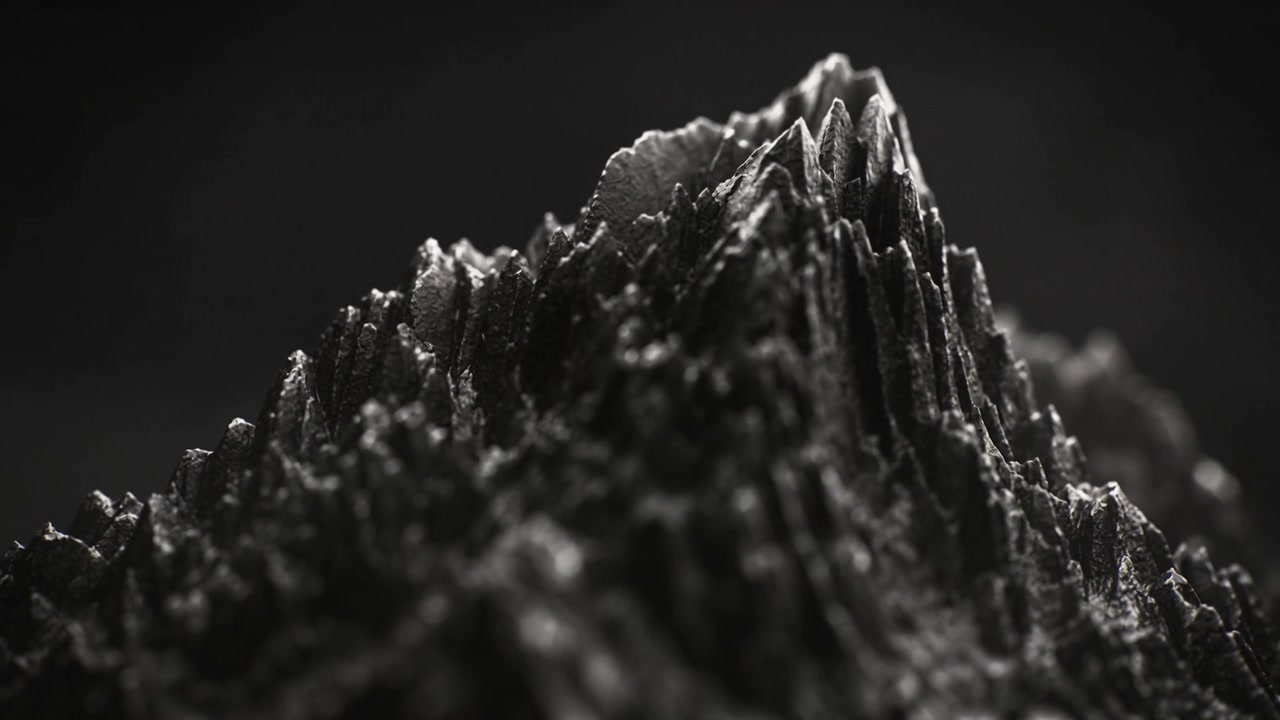 Une caméra en travelling révèle une formation sombre et déchiquetée en studio, mettant en évidence des reflets spéculaires et la texture.