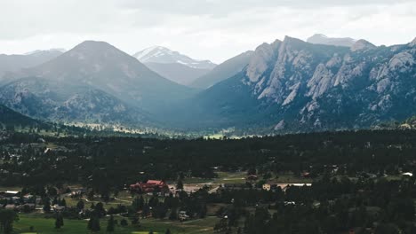 drone pan justo por encima de los parques y áreas boscosas alpinas de estes park colorado con luz brillante a través de las montañas