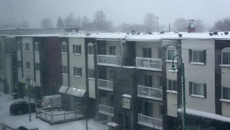 snow falls from roof of residential apartment brick building during heavy snowstorm 4k