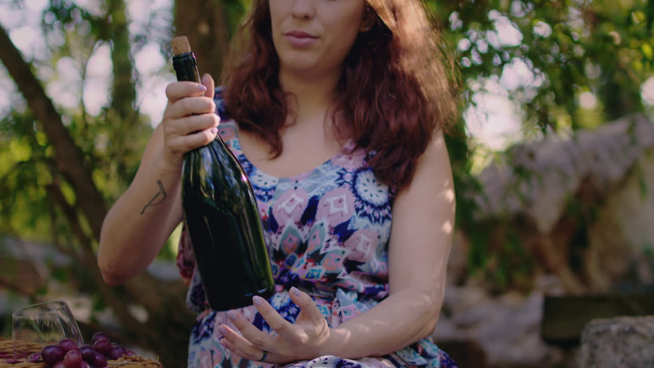 소녀는 바구니 근처에서 와인 병을 선택하고 중간  ⁇ 을 쳐다본다