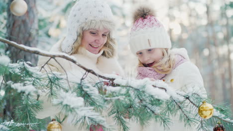 in anticipation of christmas mom and a little girl decorate in the yard of the house a christmas tre