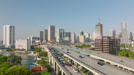 Cars-driving-on-elevated-multilane-highway.-Modern-high-rise-apartment-buildings-in-background.-Miami,-USA