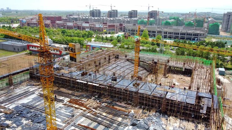 Aerial cinematic helix drone shot of big construction site with cranes and workers