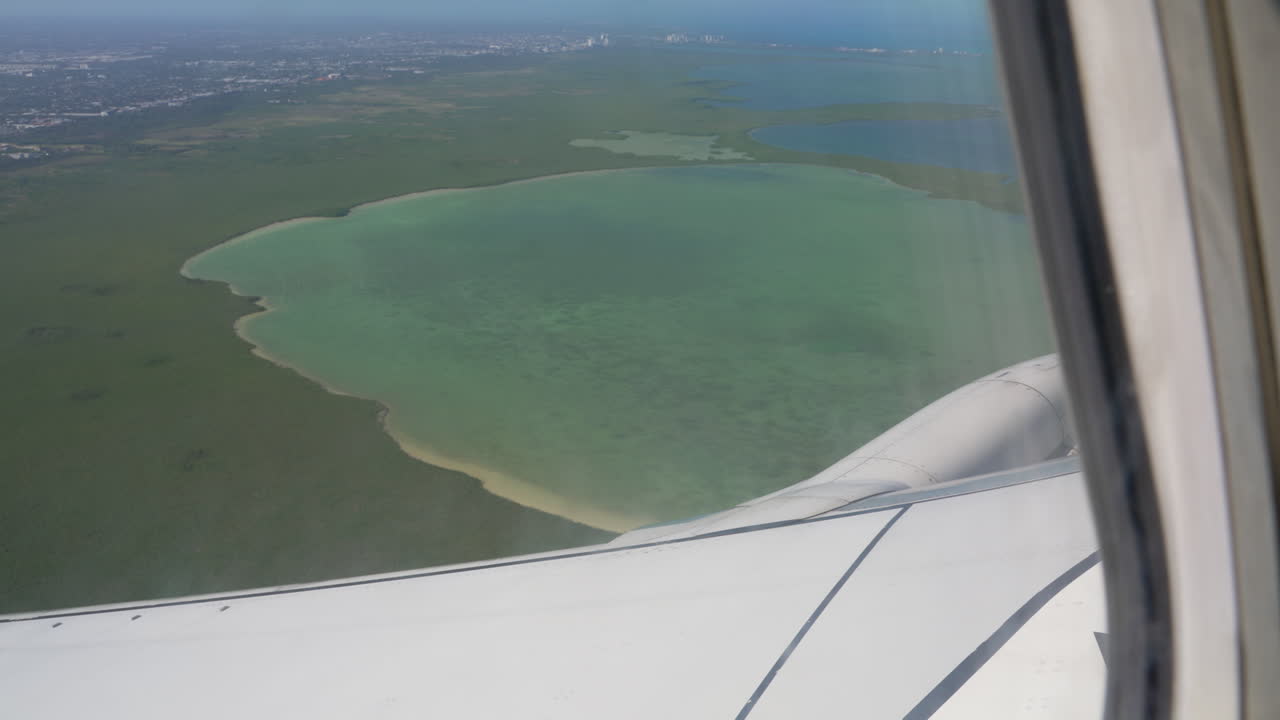 Airplane Flying Over Turquoise Blue Water Lagoon As Seen From Passenger Window.