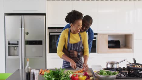 video of happy african american couple preparing meal together in kitchen