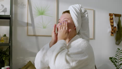 young woman applying lotion on her face