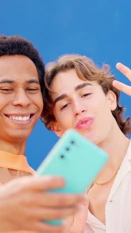 Multiracial friends taking a selfie next to a blue wall