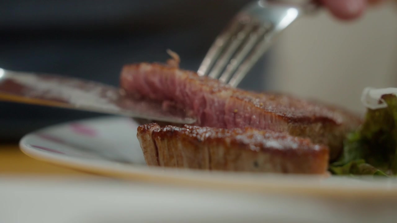 Knife cuts juicy grilled beef steak revealing pink interior texture