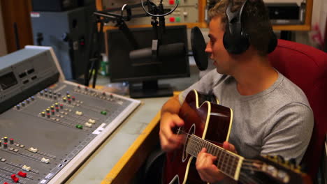 estudiante cantando y tocando la guitarra en el estudio de grabación