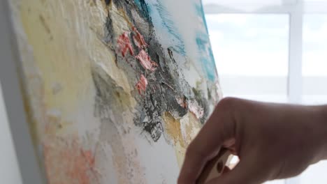 talented young artist painting on canvas with fingers and hands slow motion handheld shot of female painter with afro braids working on abstract oil painting drawing with hands while creating masterpiece then looking at camera
