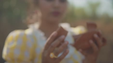 primer plano de una mujer sosteniendo dos piezas rotas de una taza de arcilla y uniéndolas cuidadosamente con sus manos