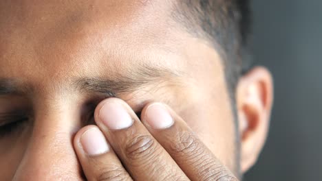primer plano de un hombre frotándose el ojo