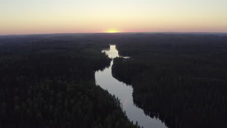 aerial shot of a narrow river in the wilderness by golden hour after sunset