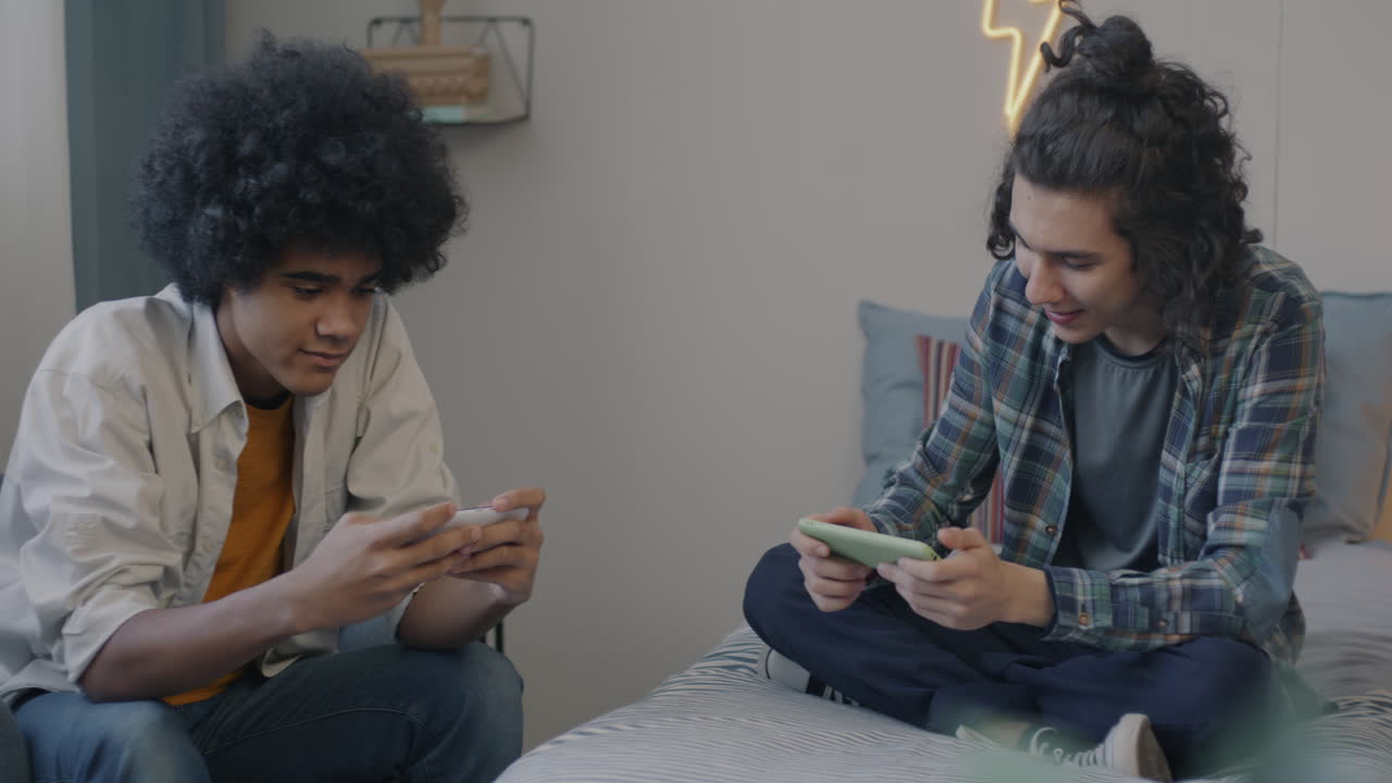 Friends Playing Mobile Games on Bed
