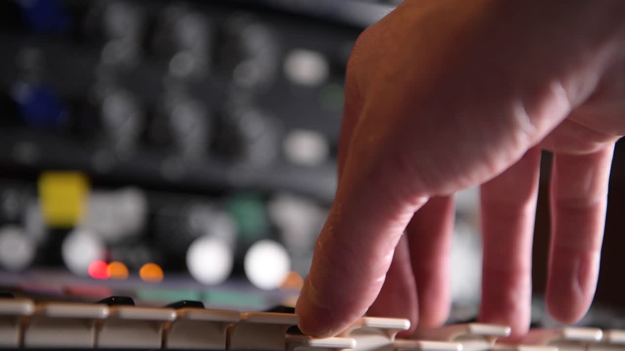 músico tocando un sintetizador analógico durante una sesión en el estudio de grabación