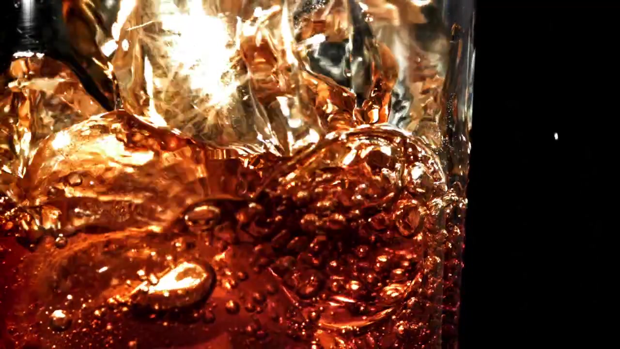 Bevanda rinfrescante alla cola versata su cubetti di ghiaccio in un bicchiere