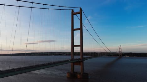 Eine-Symphonie-Aus-Licht-Und-Bewegung:-Humber-Bridge-Bei-Sonnenuntergang-Mit-Autos,-Die-Einen-Harmonischen-Rhythmus-Erzeugen,-Aufgenommen-Von-Einer-Luftdrohne