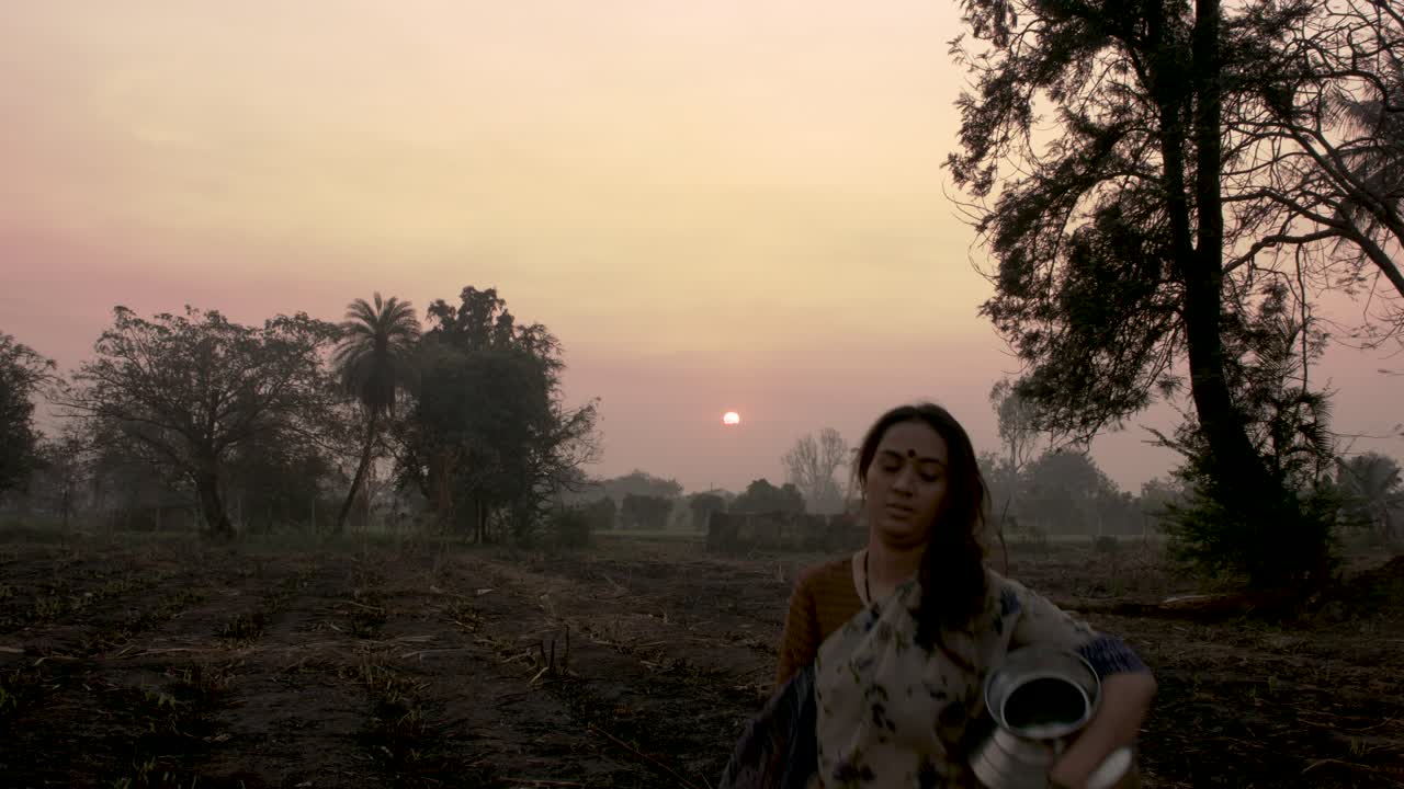 walking with metal pots to the camera during sunrise