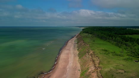 Drone-soars-over-coastline-of-steep-shores-and-green-fields