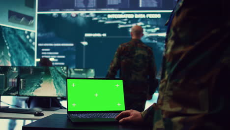 oficial del ejército estudia una pantalla verde aislada en una computadora portátil en la sala de control