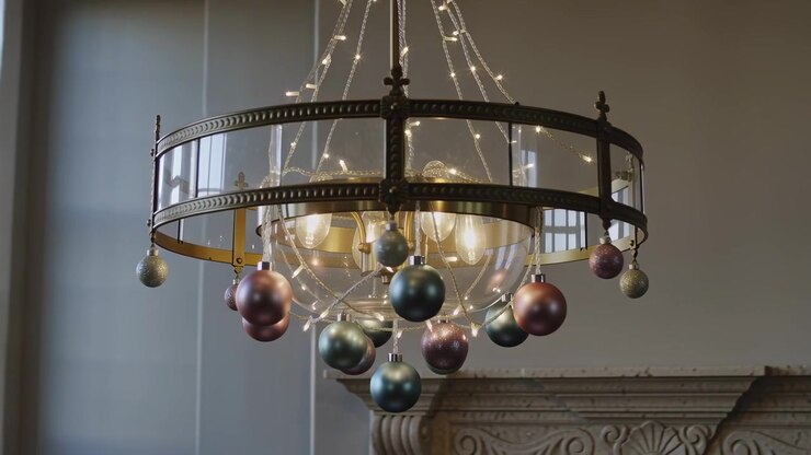 Camera pulling back bronze fixture swinging with lit bulbs and pastel orbs, revealing window