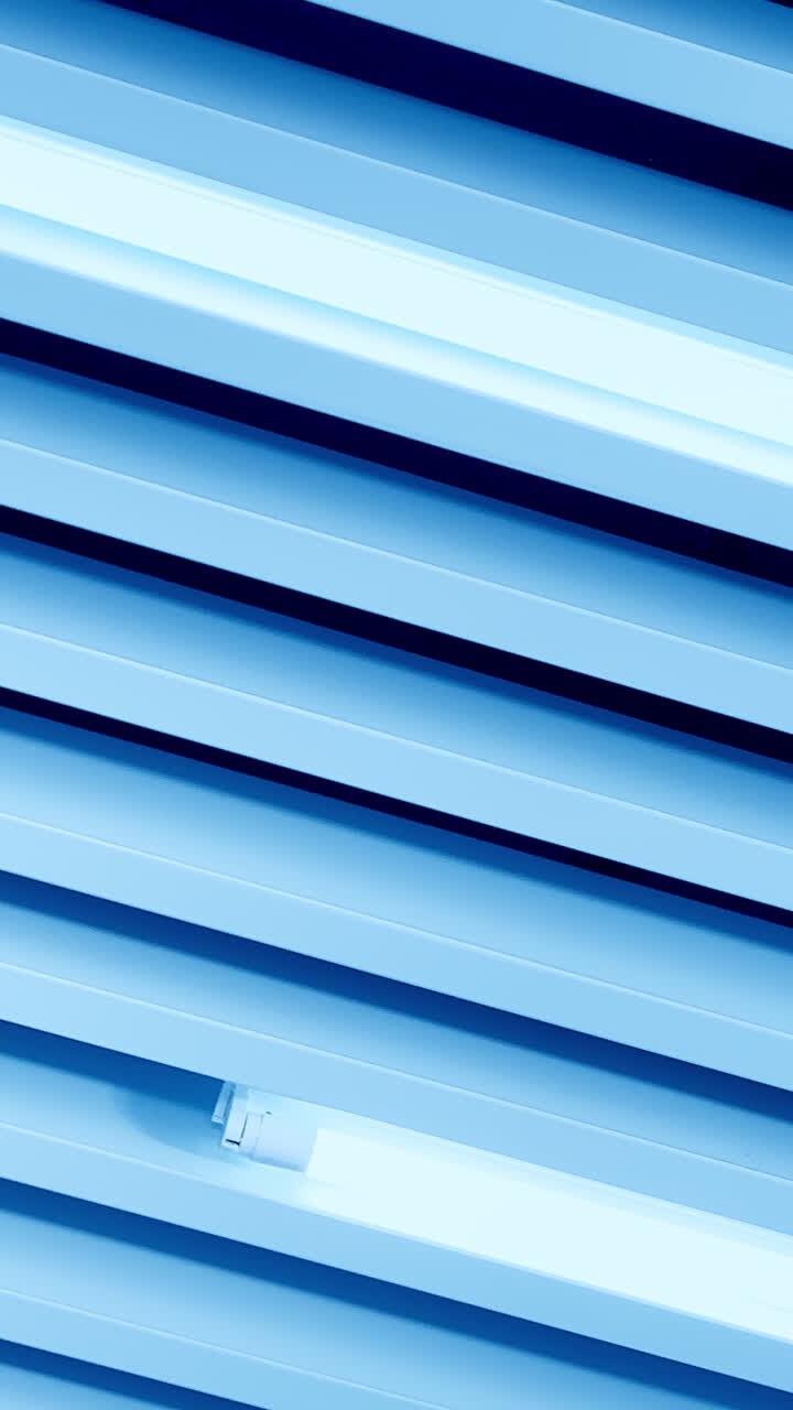White light of long led lamps among the decorative panels on the ceiling. View from below. Vertical video
