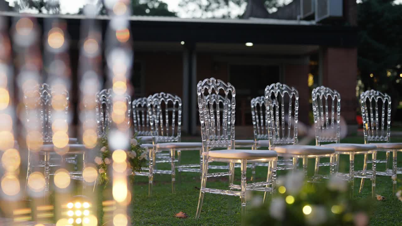 Panoramica introduttiva di un allestimento per una cerimonia di matrimonio all'aperto con corridoio floreale e sedie trasparenti