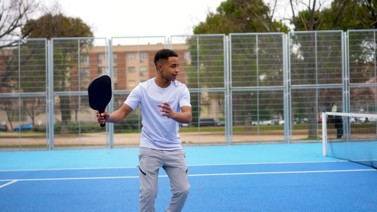 Young Man Playing Pickleball on an Outdoor Blue Court