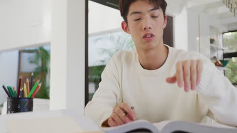 thoughtful asian young boy studying in living room at home