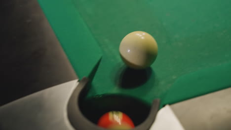 cue stick strikes white billiard ball on green pool table as colorful balls are scattered. hand grips cue, ready for precise shot. close-up shot captures motion and details of billiards play