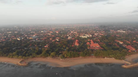 tilt down shot of sanur beach at bali indonesia at sunrise, aerial