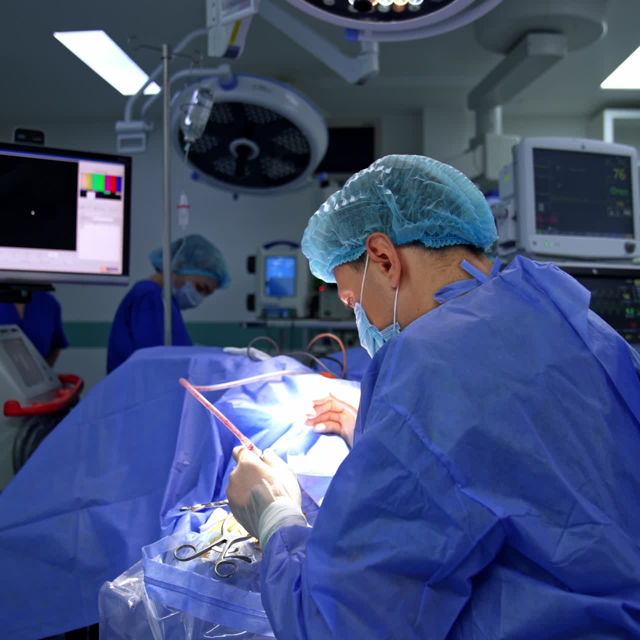 Back view of a doctor who bent over the patient conducting surgery. Neurosurgeon working in the modern surgical room with lots of advanced equipment
