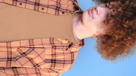cute young happy student on blue background looking at phone cute young happy student on blue background looking at phone curly redhaired guy is crazy happy internet search technologies