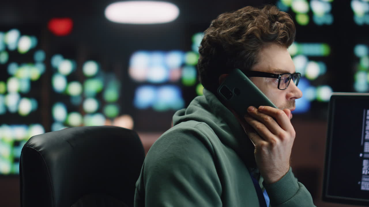 IT man talking cellphone coding computer at workplace closeup. Coder guy calling