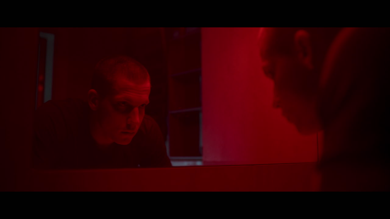 Uomo che si guarda in uno specchio illuminato di rosso