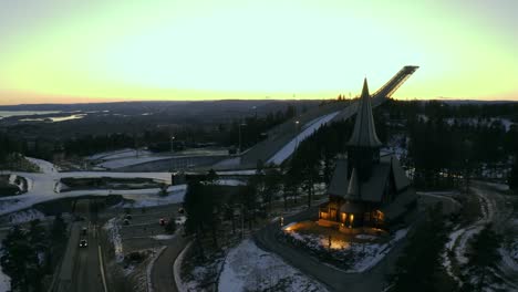 Iglesia-De-La-Capilla-De-Holmenkollbakken,-Oslo-Winter-Park-Winter-Park-Tryvann-Drone-Envuelto-Con-Salto-De-Esquí-Al-Atardecer-Holmenkollen