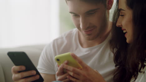 happy couple using mobile phones together at home