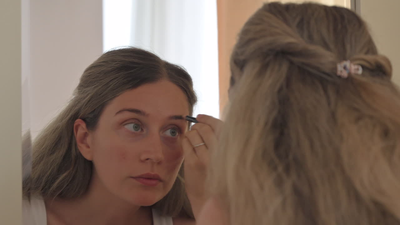Woman shaping her eyebrows in the mirror