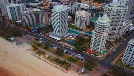 coastal road traffic and tourists on sandy shore at gold coast city in queensland, australia